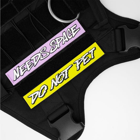 Black dog harness with 'Needs Space' and 'Do Not Pet' PVC patches on a white background