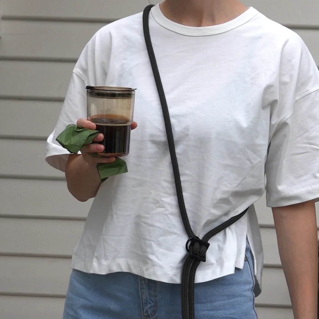 wearing black handsfree leash across chest with coffee to go