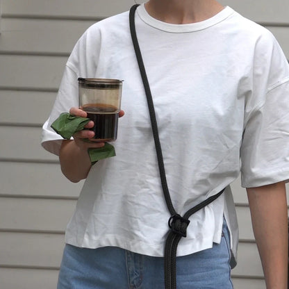 wearing black handsfree leash across chest with coffee to go