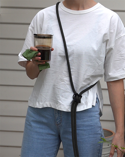 wearing black handsfree leash across chest with coffee to go