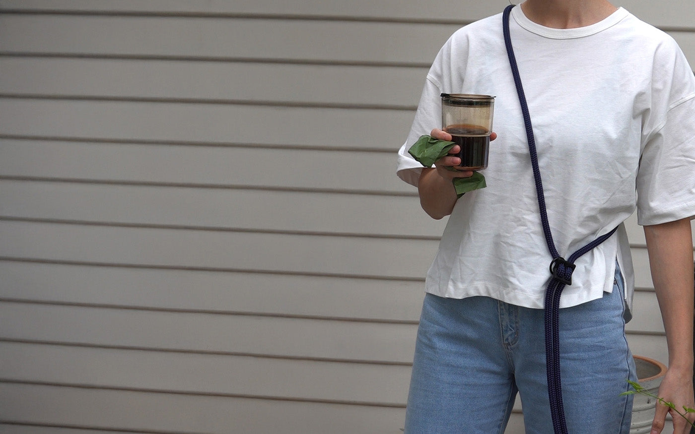 wearing navy blue hands-free leash around the shoulders while carrying a poop bag and coffee
