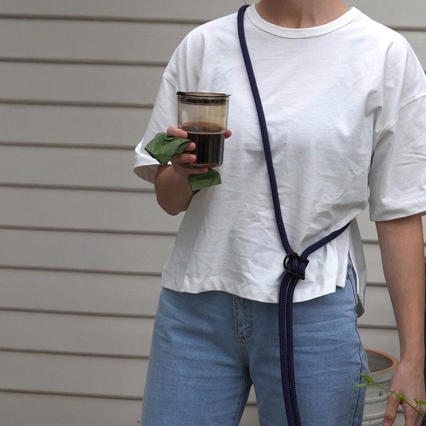 wearing navy blue hands-free leash around the shoulders while carrying a poop bag and coffee