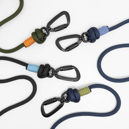 Four carabiner clips attached to braided rope dog leads in different colors, arranged on a clean white background. The rope colors include army green, black, navy blue, with accent wraps in orange, light blue, lavender, and moss green.